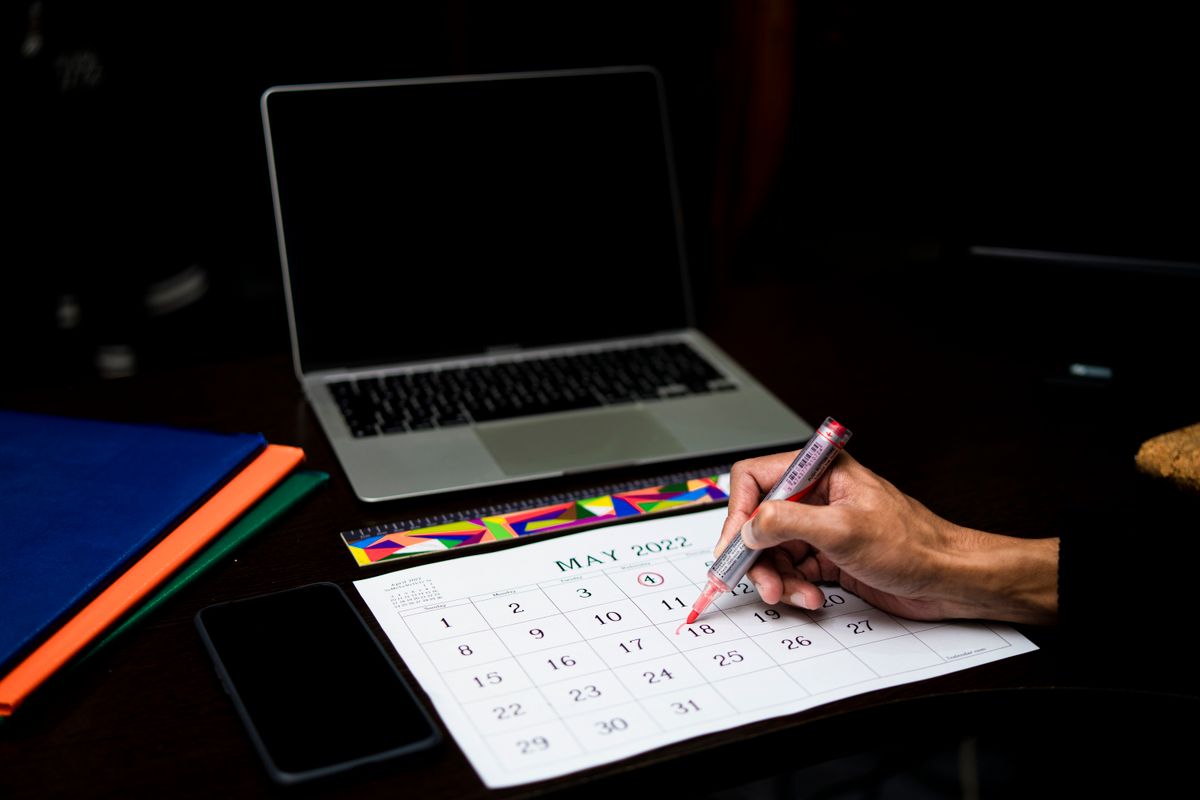 A calendar being marked beside a laptop